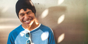 Smiling boy in a blue shirt with sunglasses, enjoying a sunny day, embodying carefree childhood fun.