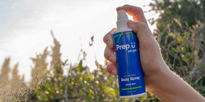 Hand holding a Prep U all-natural Citrus Mint body spray with a sunny backdrop.