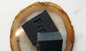 Charcoal cleansing soap bars resting on a unique agate slice for detoxifying skincare.