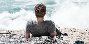 Young boy relaxing on the beach, enjoying the ocean view on a warm sunny day.