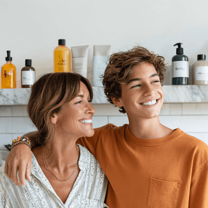 A smiling mother and son standing together, surrounded by various hygiene products on a shelf.