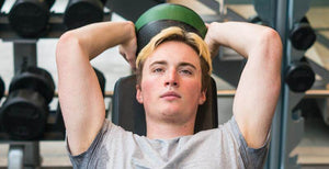 Young man exercising with a medicine ball while focusing on his fitness routine in the gym.