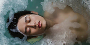 A young man enjoying a relaxing soak in a bubble-filled bath, eyes closed, embracing tranquility.