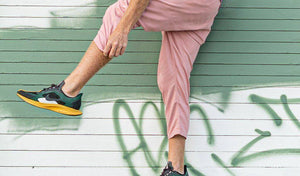 Man in trendy athletic wear demonstrating a fun and active fitness routine against a colorful wall.