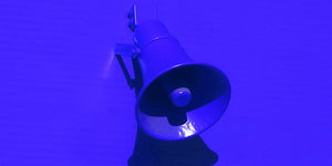 A blue-toned image of a loudspeaker mounted on a wall, ready to announce exciting news.