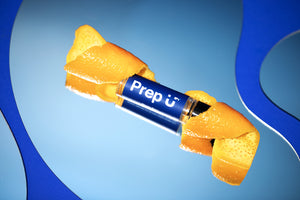 Vibrant orange peels wrapping a tube labeled 'Prep U' on a blue reflective surface.