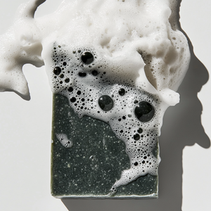 Artisan dark soap with bubbling foam, perfect for eco-friendly skincare and natural cleansing.