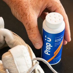 Hand reaching for Prep U Powder next to a white sneaker