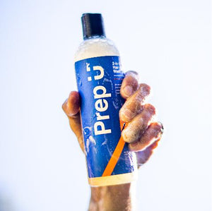 Hand holding a bottle of Prep 2-in-1 Hair and Body Wash, featuring a blue label and a bold logo.