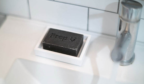 Prep U Charcoal Bar soap on white dish next to modern faucet, highlighting personal hygiene choices.