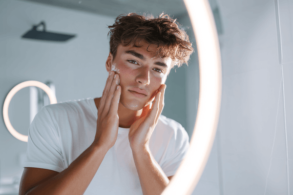 Teen athlete applying natural skincare in bathroom mirror to combat post-game breakouts and maintain healthy skin.
