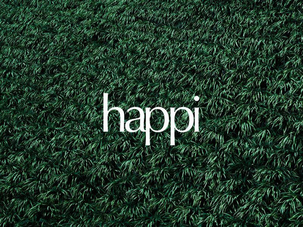 Stylish logo of 'happi' set against a lush green grass background, radiating freshness and positivity.