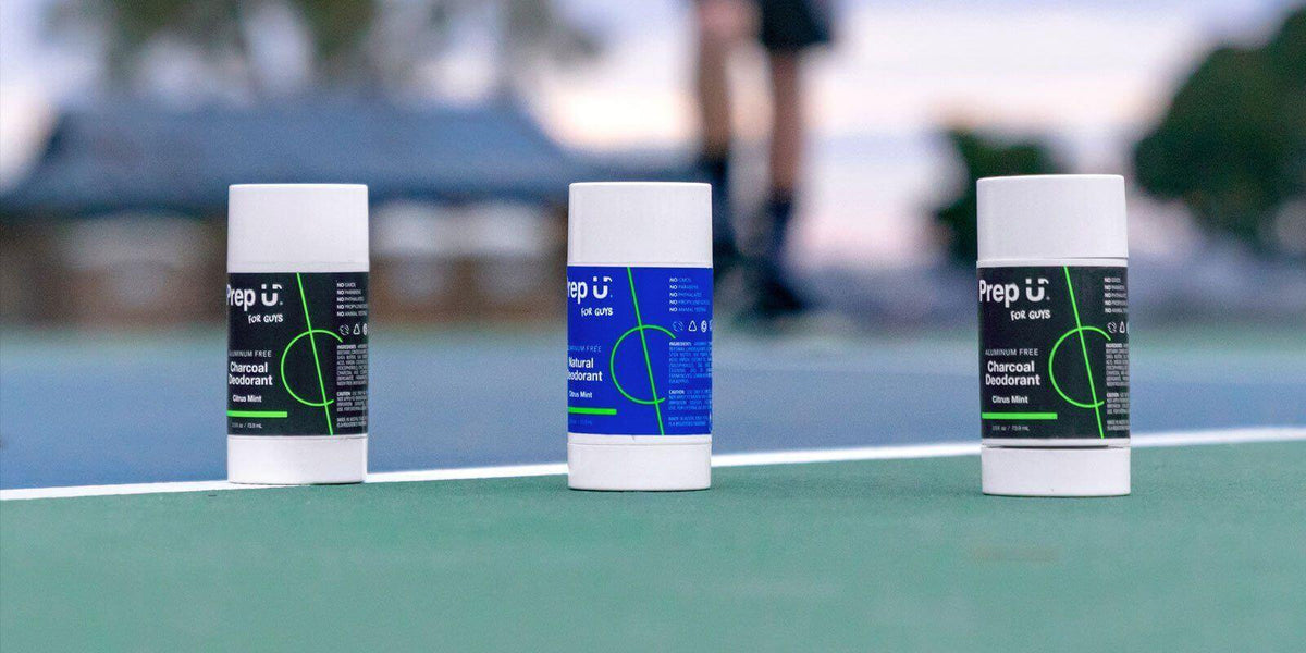 Three varieties of Prep U natural deodorant placed on a tennis court, showcasing effective sweat solutions.