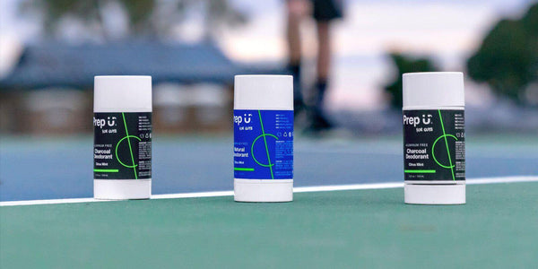 Three varieties of Prep U natural deodorant placed on a tennis court, showcasing effective sweat solutions.