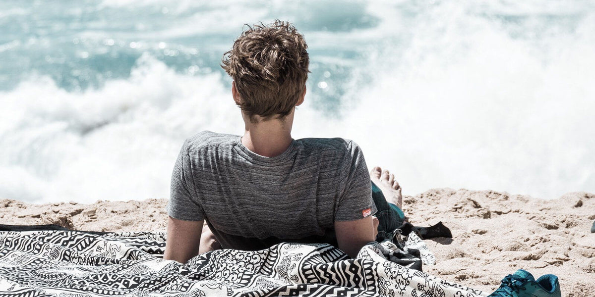 Young boy relaxing on the beach, enjoying the ocean view on a warm sunny day.