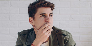 Thoughtful young boy with hand on face, reflecting on age-appropriate conversations in the #MeToo movement.