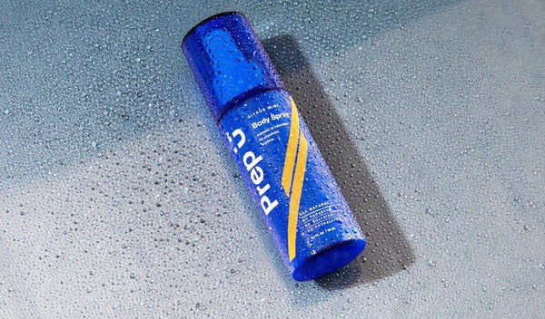 A vibrant blue body spray can with droplets of water on its surface, showcasing its fresh appeal.