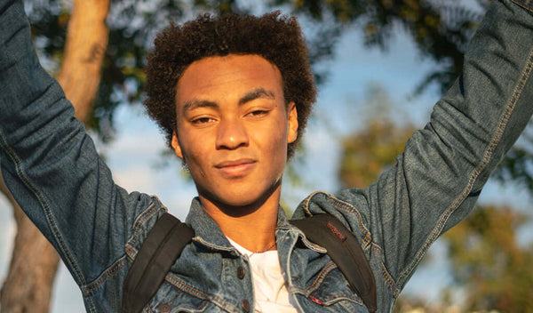 Confident teenager enjoying the outdoors, wearing a denim jacket and backpack, ready for a fun day.