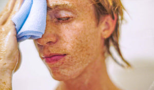 Person washing their face with a soft cloth, highlighting the importance of proper skincare techniques.