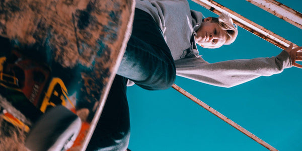 Skateboarder performing a trick under a blue sky, showcasing young athletic energy and adventure.