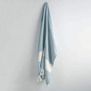 Blue and white striped towel with tassels on a light gray background