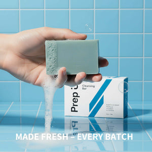 Hand holding a Prep U soap bar with a box labeled 'Prep' on a blue tiled background