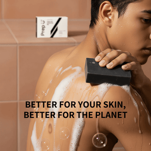 Teen using a black soap bar on their shoulder with a soapy lather, in a bathroom setting.