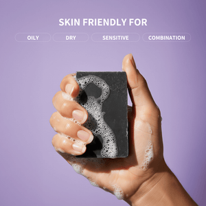 Hand holding a soap bar with foam, against a purple background with text indicating skin types.