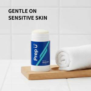 Deodorant stick with towel on wooden board against white tiled wall