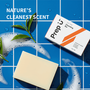 Prep U Bar of soap and packaging on a blue tiled background with green leaves.